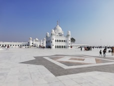 people walking on street near white concrete building under blue sky during daytime