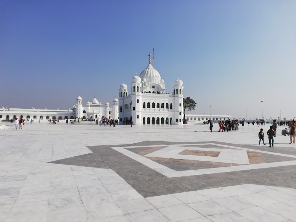 people walking on street near white concrete building under blue sky during daytime