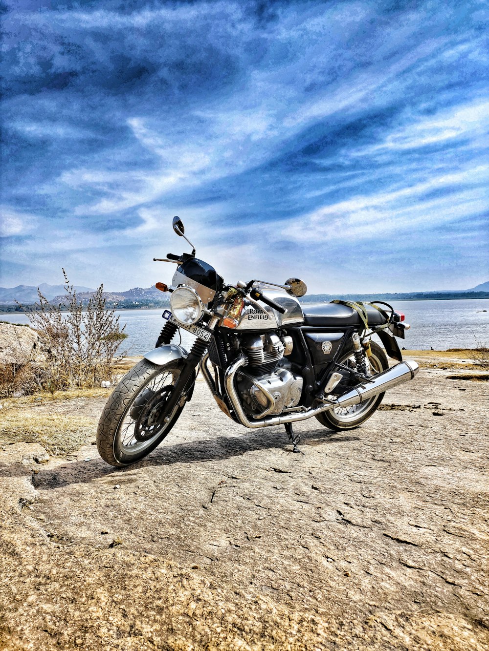 black and silver cruiser motorcycle on brown sand near body of water during daytime