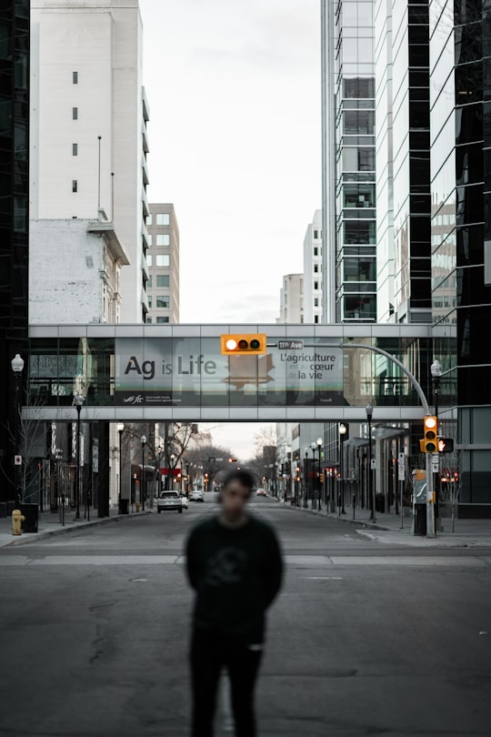 man in black jacket standing on pedestrian lane during daytime in Regina Canada