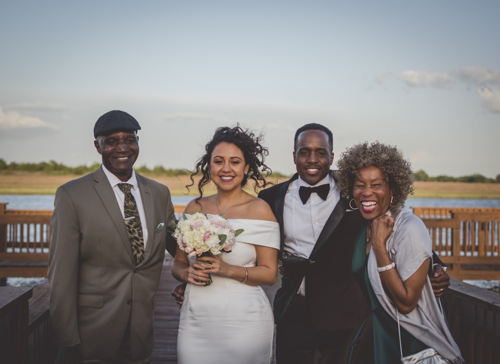 man in black suit jacket beside woman in white dress holding bouquet of flowers