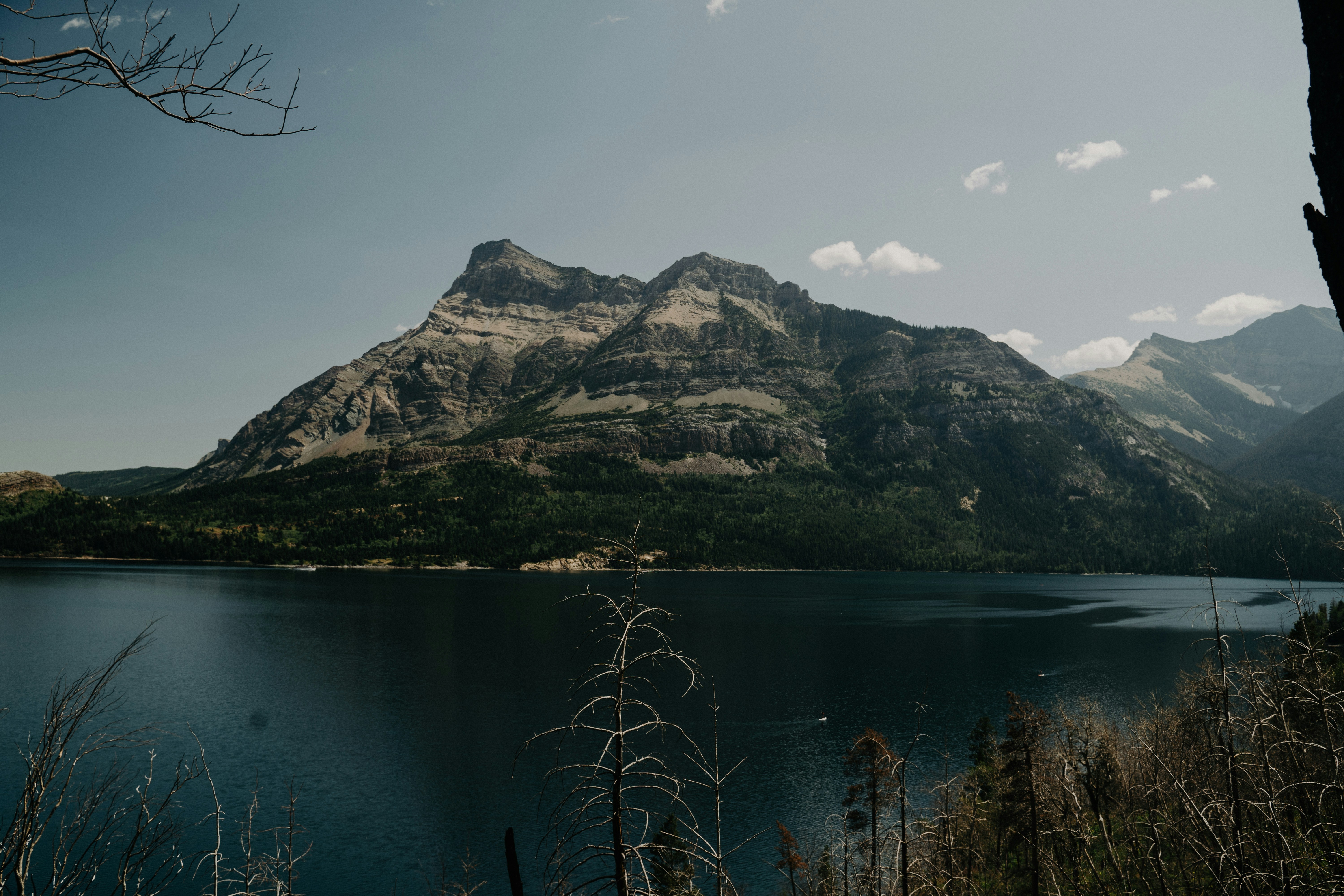 lake near mountain under white sky during daytime
