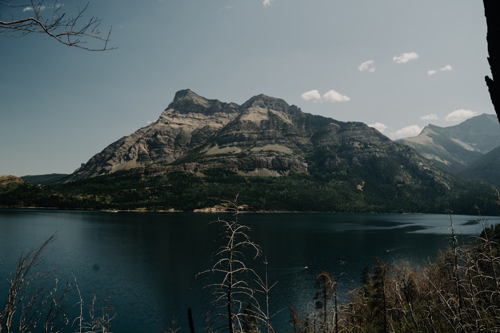 lake near mountain under white sky during daytime