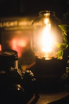 A softly glowing golden hour light filters through a window onto a minimalist black desk with a vintage film camera and a notebook.