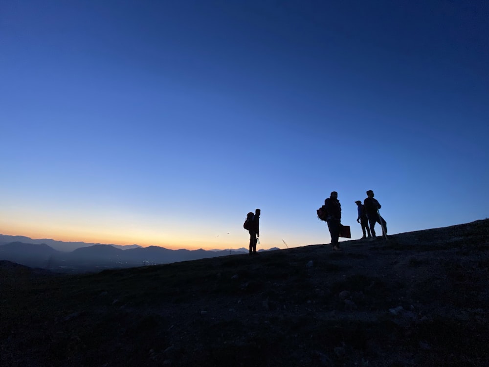 silhouette of people on top of mountain during sunset