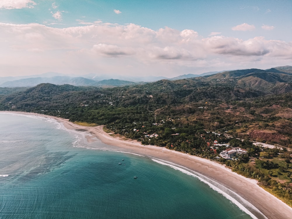 aerial view of green and brown mountains beside blue sea during daytime