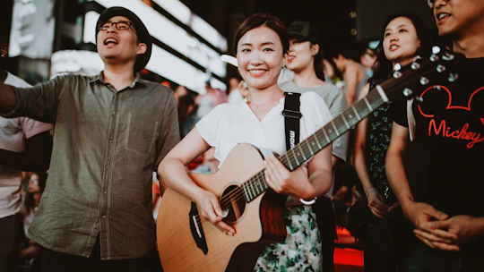 A lively folk music gathering under warm evening lights with musicians and audience sharing smiles.