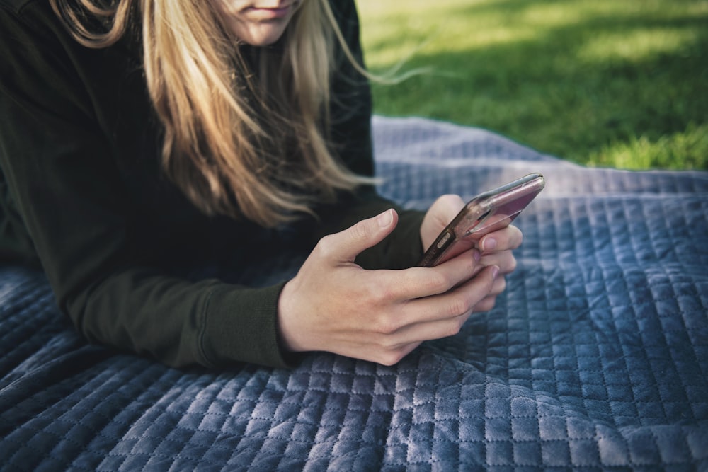 donna in camicia nera a maniche lunghe che tiene lo smartphone