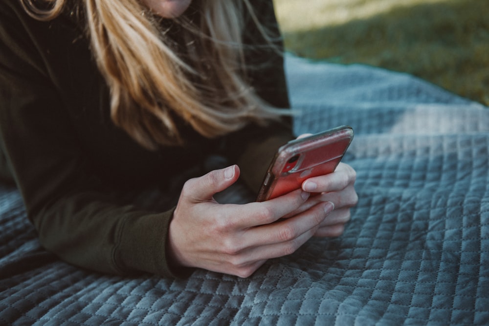 woman in black long sleeve shirt holding red smartphone