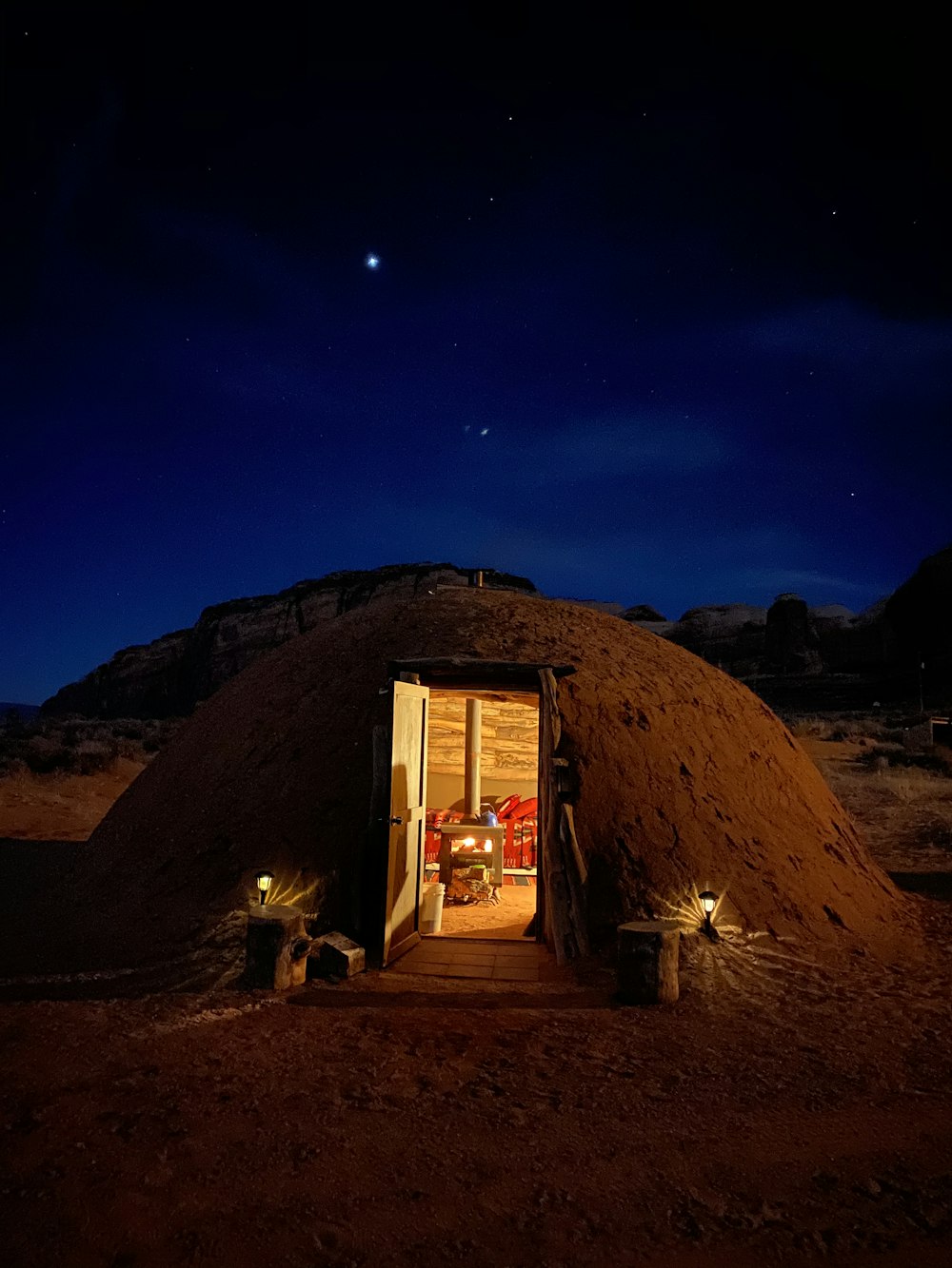 brown wooden house near brown mountain under blue sky during night time