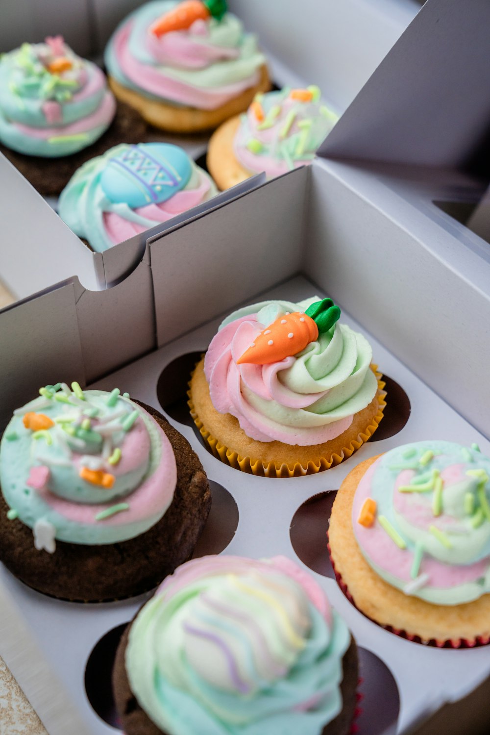 Cupcakes mit weißer Glasur und grüner und rosa Glasur oben drauf