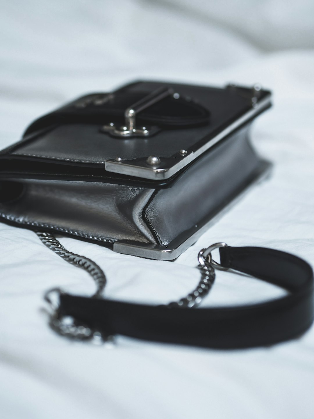black leather sling bag on white textile