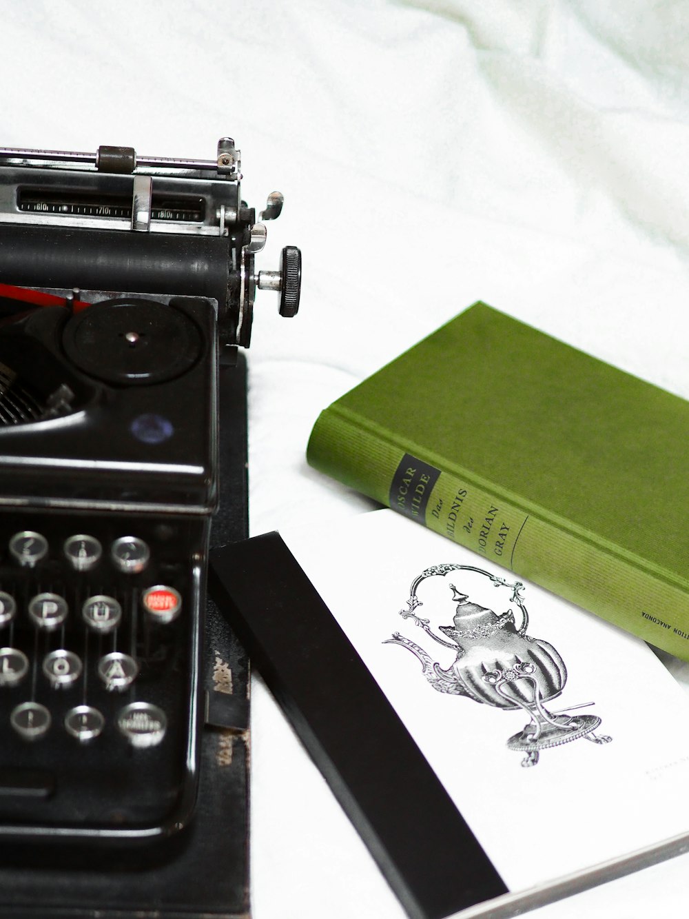green and black typewriter beside green book