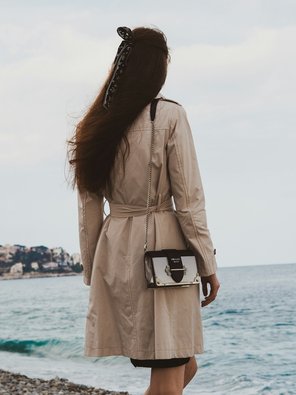 woman in brown coat standing near sea during daytime
