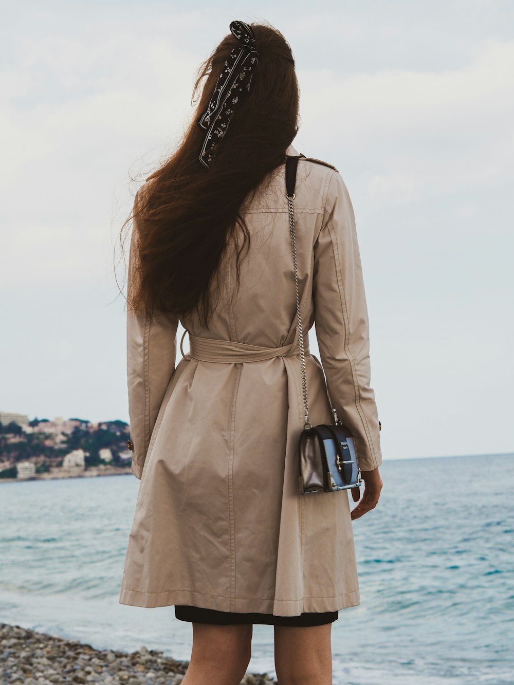 woman in brown coat standing near sea during daytime