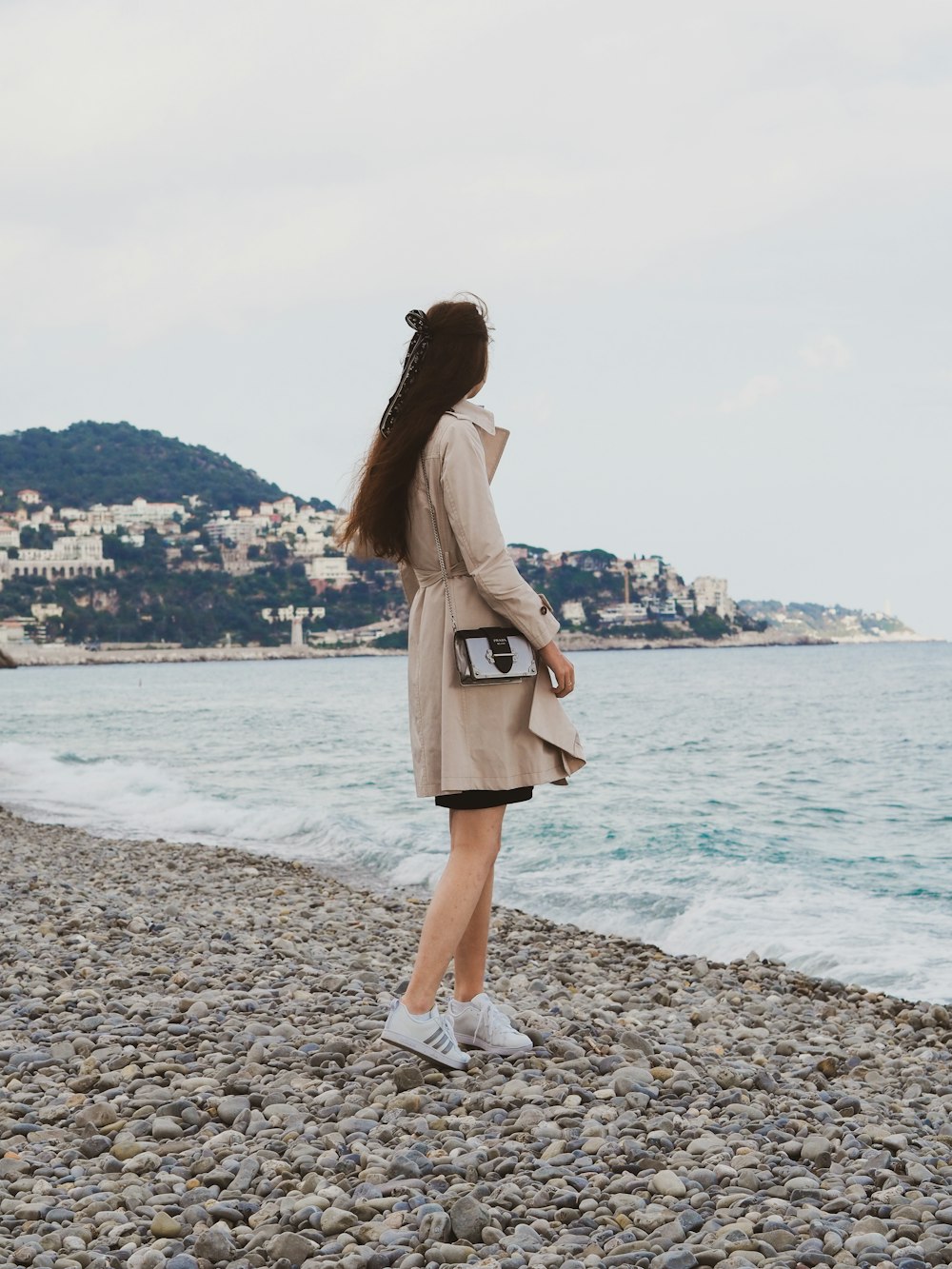 woman in brown coat standing on beach during daytime