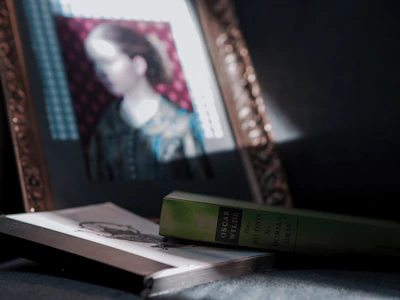 A shadowy portrait of a classic gothic author framed by dark velvet curtains.