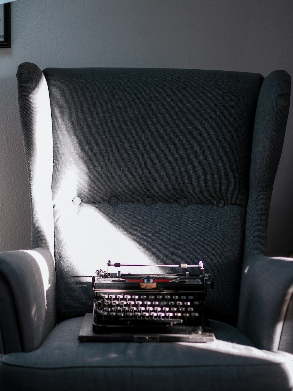 black and gray braille typewriter on gray sofa