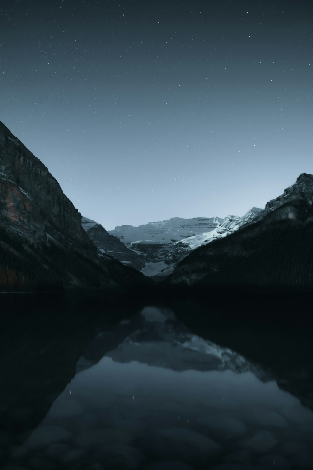 lake in between mountains under blue sky during daytime