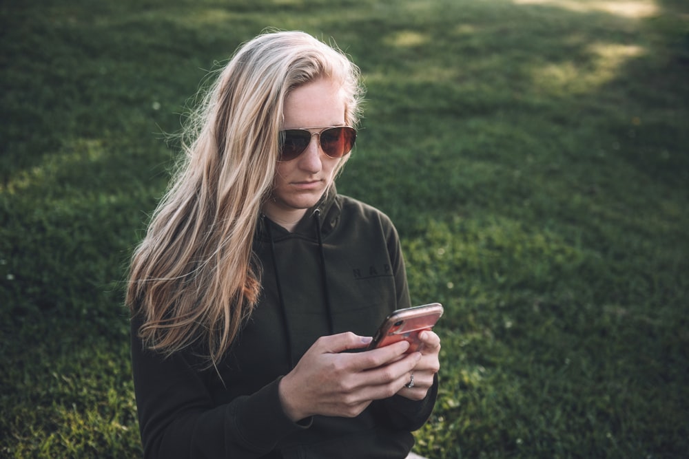 Frau in schwarzer Jacke hält Smartphone