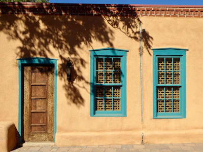 Turquoise window frames set into an adobe wall in Santa Fe