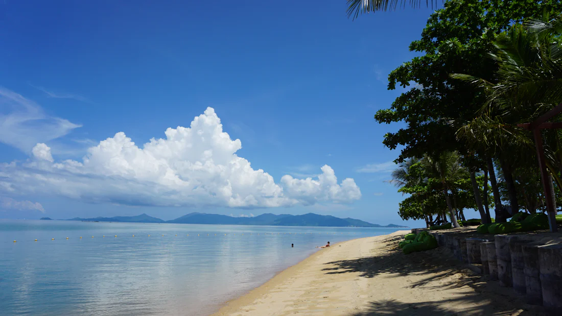 หาดทรายสงบร่มเงามะพร้าวฝั่งอ่าวไทย มองเห็นเกาะอยู่ไกล ๆ