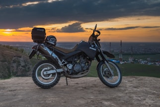 A rugged adventure motorcycle parked on a scenic mountain trail at sunset.