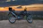 A rugged motorcycle parked on a rocky trail at sunset, gear strapped securely.