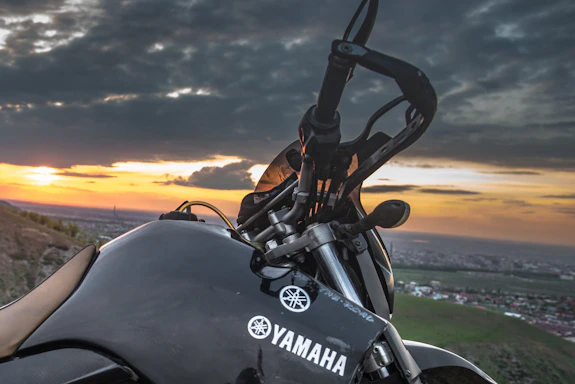 A friendly Yamaha motorcycle parked near a sunset-lit urban street.
