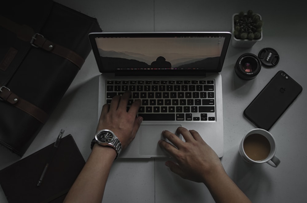 person using macbook pro on white table