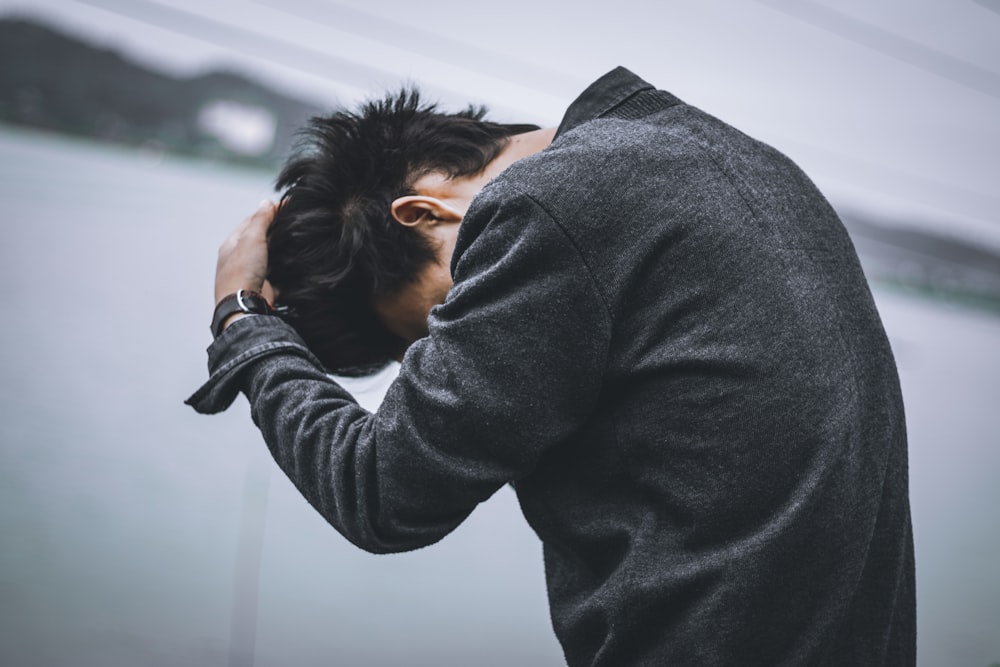 man in black long sleeve shirt covering his face