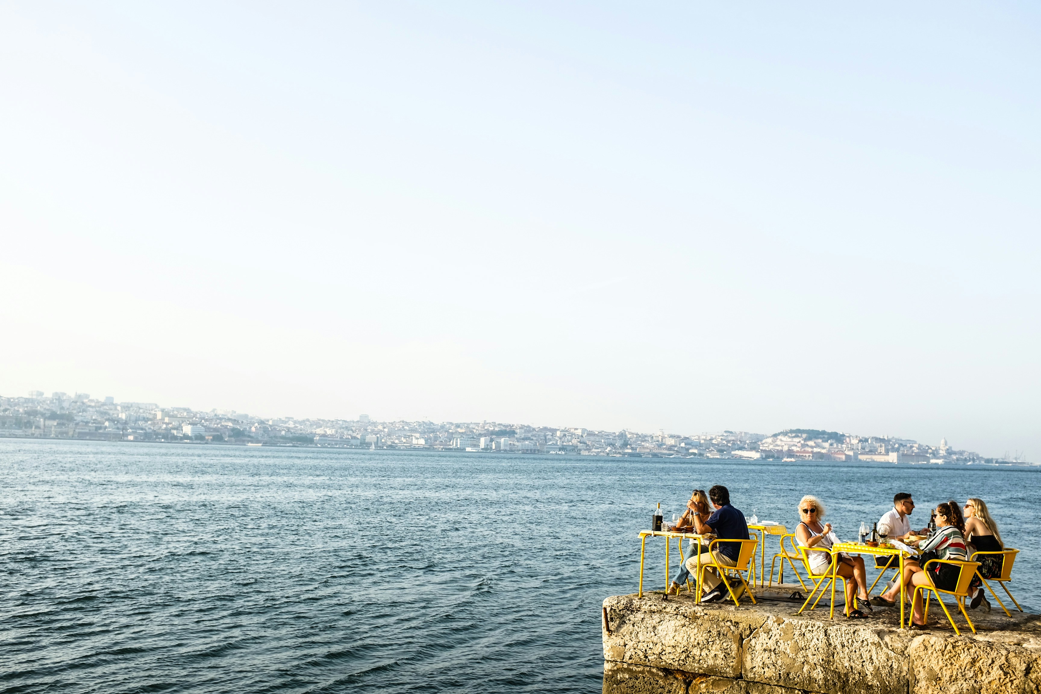 man and woman sitting on brown rock near body of water during daytime, 