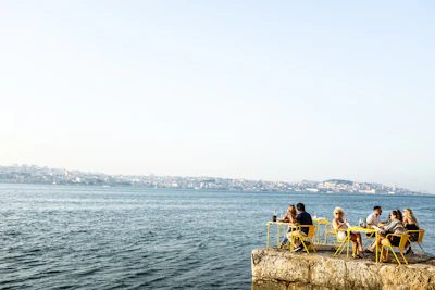 man and woman sitting on brown rock near body of water during daytime