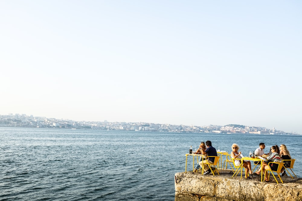 man and woman sitting on brown rock near body of water during daytime