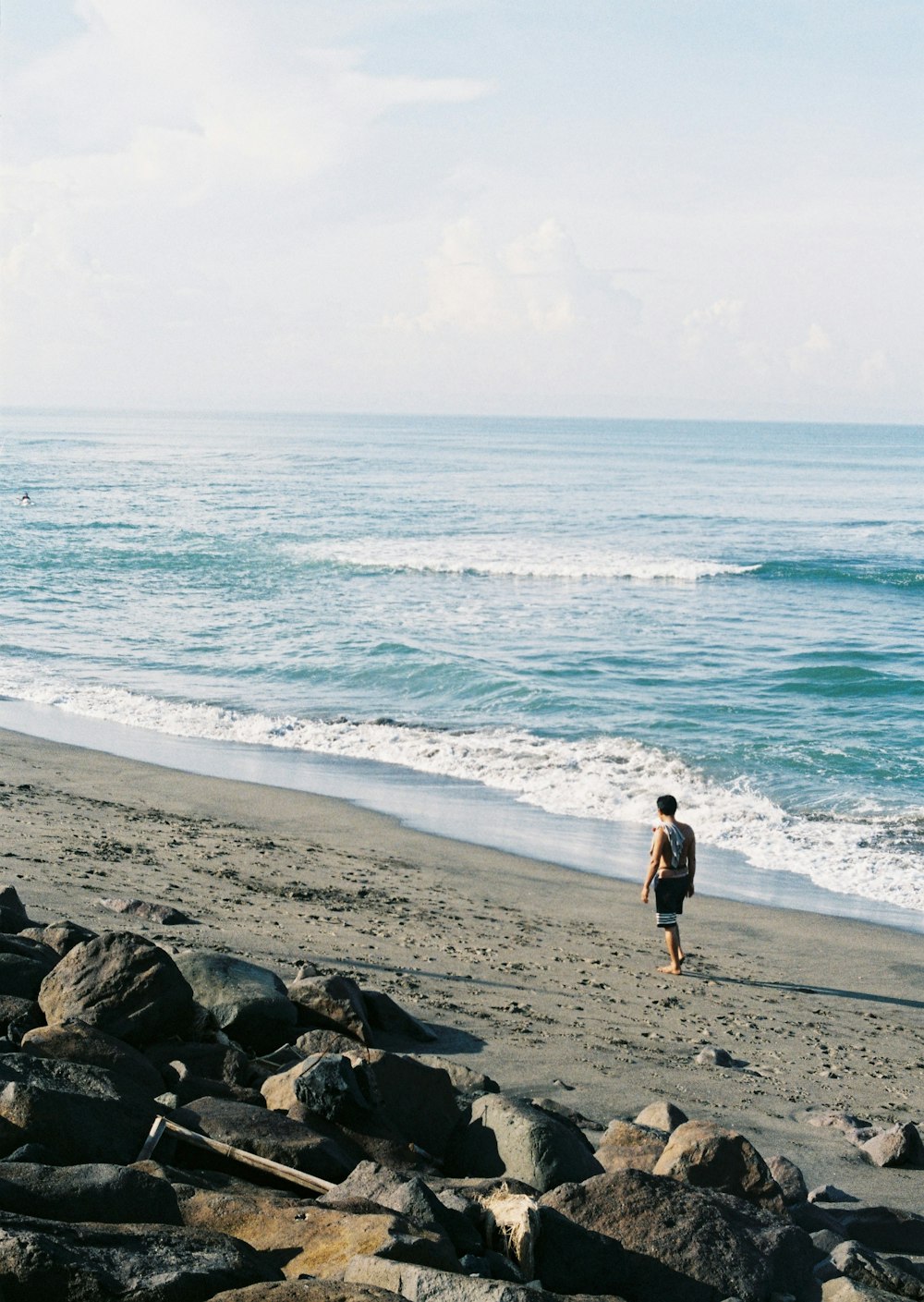 woman in black tank top walking on beach during daytime