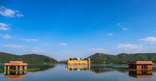 brown concrete building near body of water under blue sky during daytime in Jal Mahal India