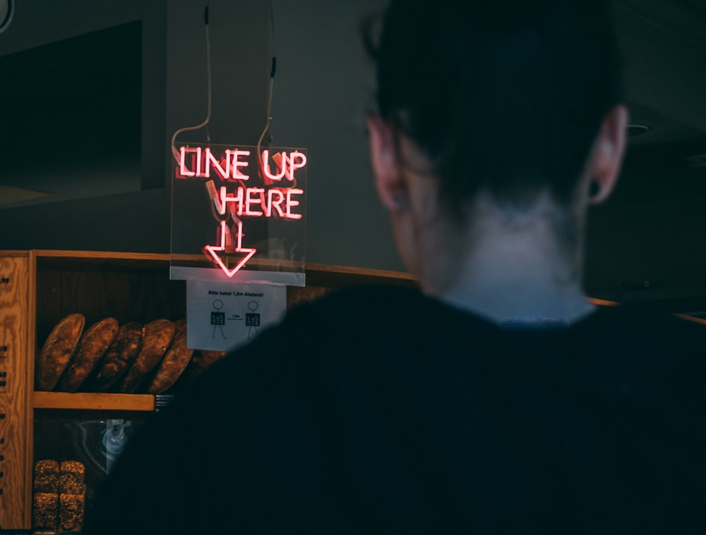 man in black shirt standing near red and white led signage