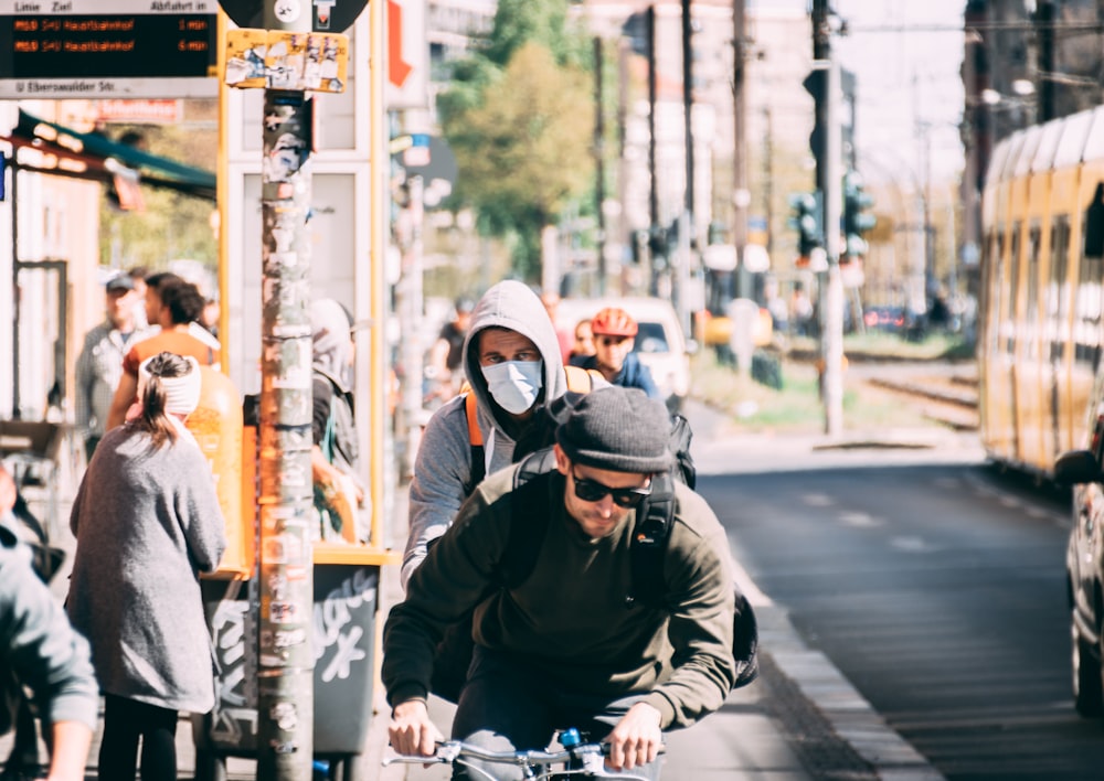 man in black jacket and helmet riding bicycle on road during daytime