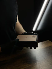 A delivery person handing over a sleek iPhone box to a happy customer at their doorstep.