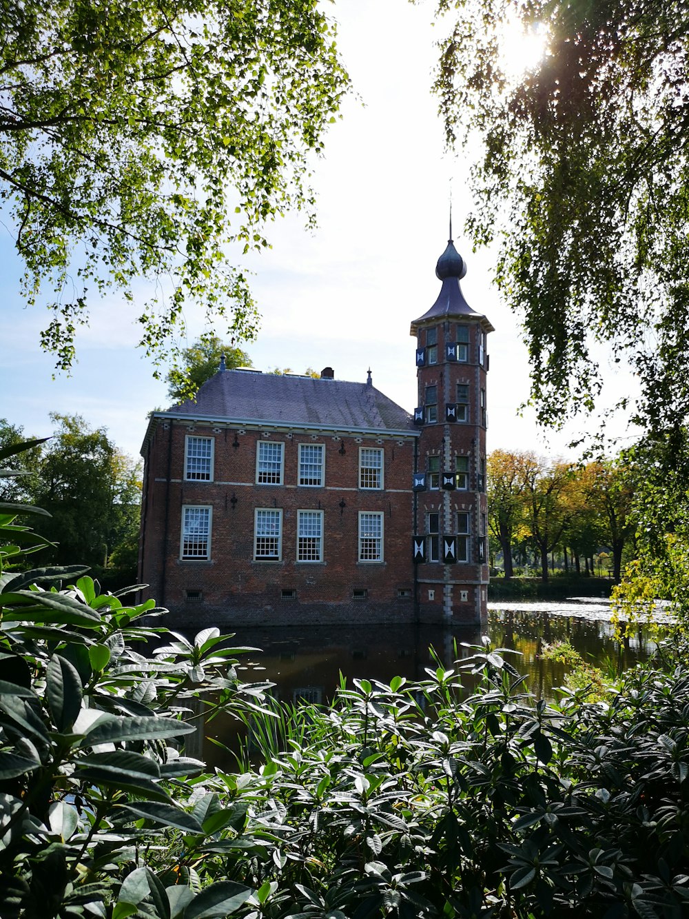 brown concrete building near green trees and river during daytime