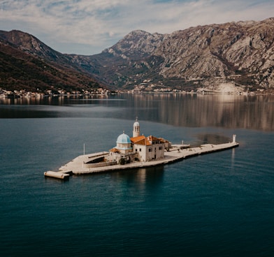 white and brown boat on body of water near mountain during daytime