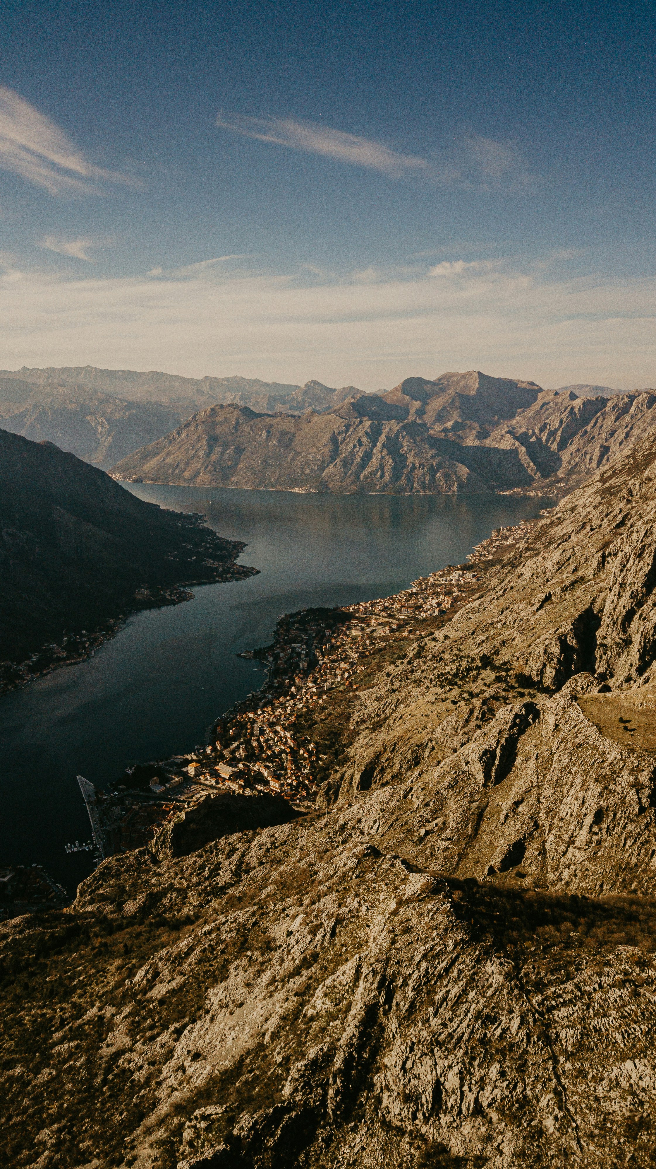 brown rocky mountain beside lake during daytime