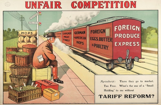 A railway scene depicting a freight train labeled 'Foreign Produce Express' carrying goods like 'Foreign Fruit', 'Chicago Meat Trust', 'German & American Hops', and 'Foreign Eggs, Butter & Poultry'. A man, wearing a suit and bowler hat with a paper that says 'Rate on Demand', sits on crates beside baskets labeled 'Hops' and 'Eggs'. A signpost with 'Foreign' and 'English' highlights economic themes. The caption below the image reads: 'Agriculturist: There they go to market, Tax Free. What&rsquo;s the use of a &ldquo;Small Holding&rdquo; to me without Tariff Reform?'