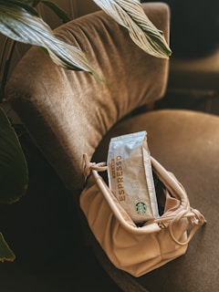A cozy indoor scene with a Janice Carteras bag resting on a chair next to a cup of coffee.