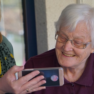 woman in brown button up shirt holding white smartphone