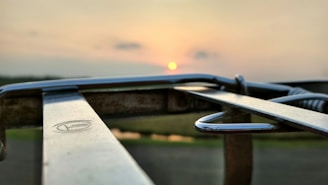 Close-up of a metal parking barrier with reflective stripes at sunset.