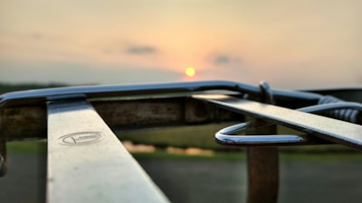 Close-up of a metal parking barrier with reflective stripes at sunset.
