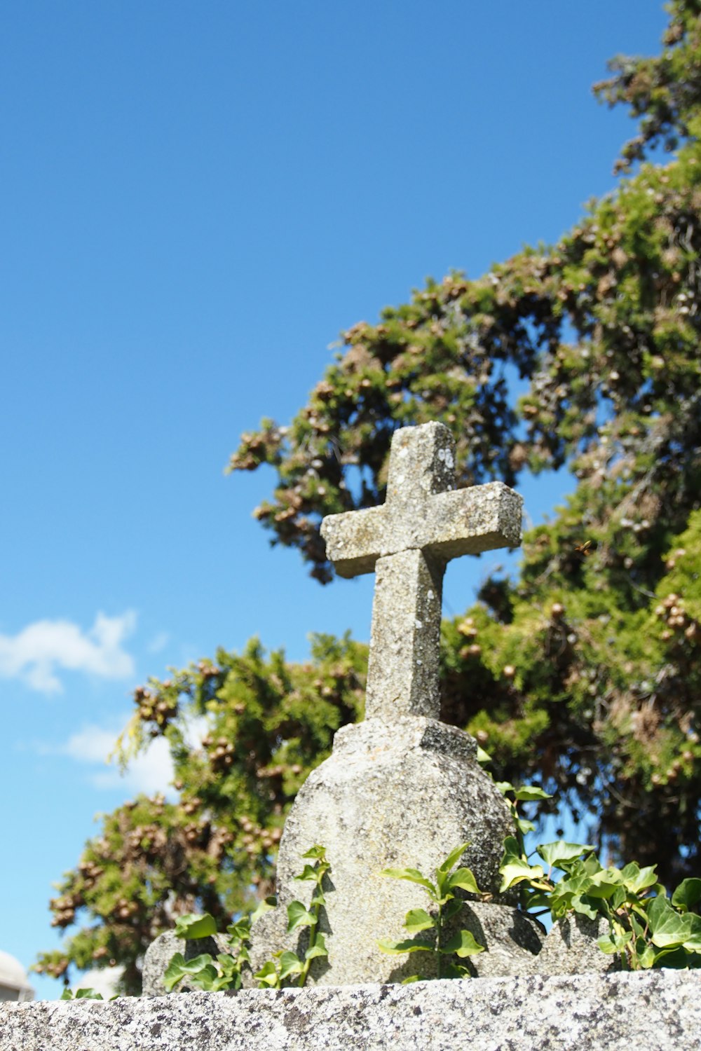 gray cross on gray stone under blue sky during daytime