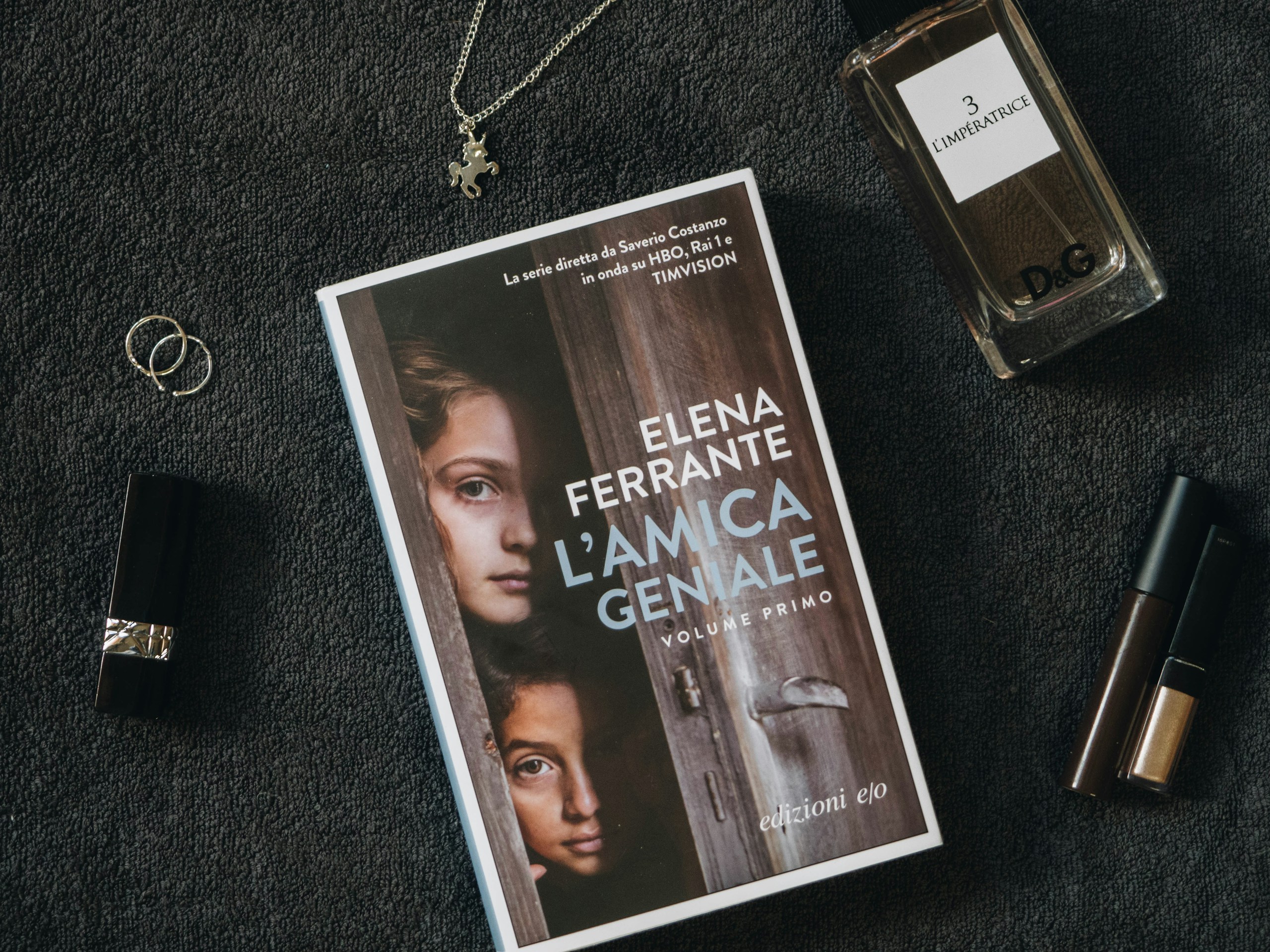 a photo of the Italian edition of My Brilliant Friend surrounded by makeup, perfume, and jewelry