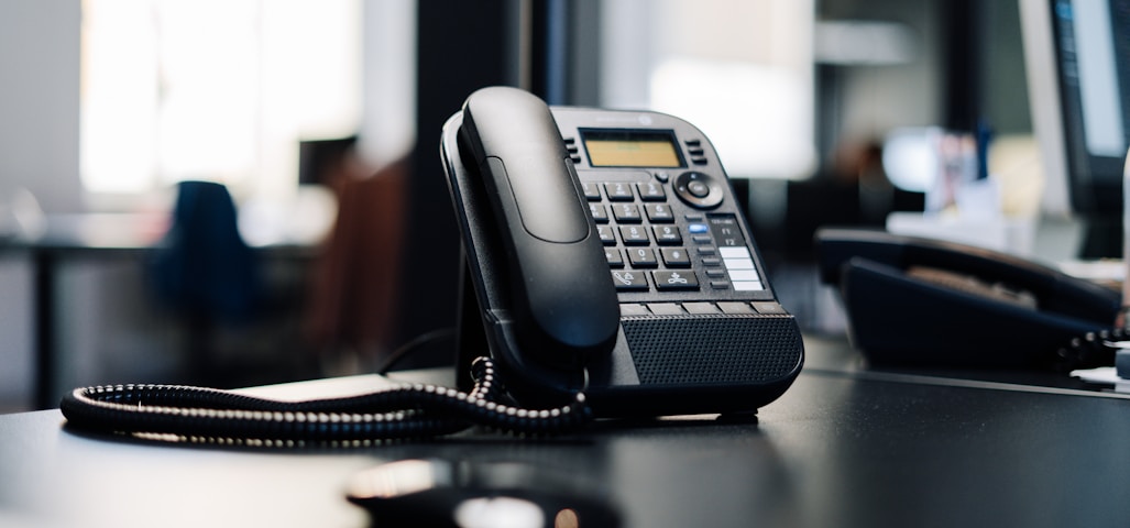 black ip desk phone on black wooden table